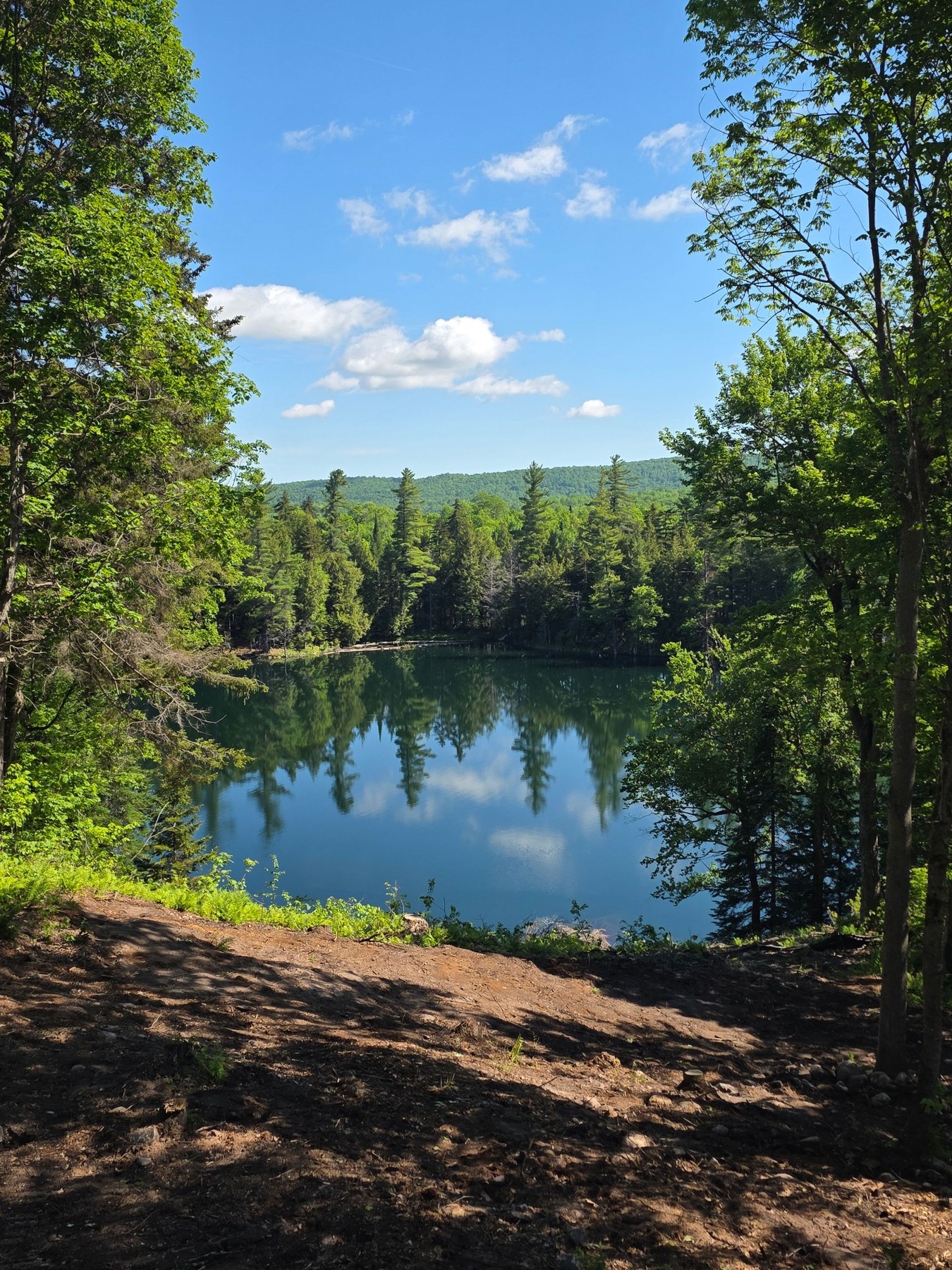 Little Kettle Pond from above, framed by forest and sky.